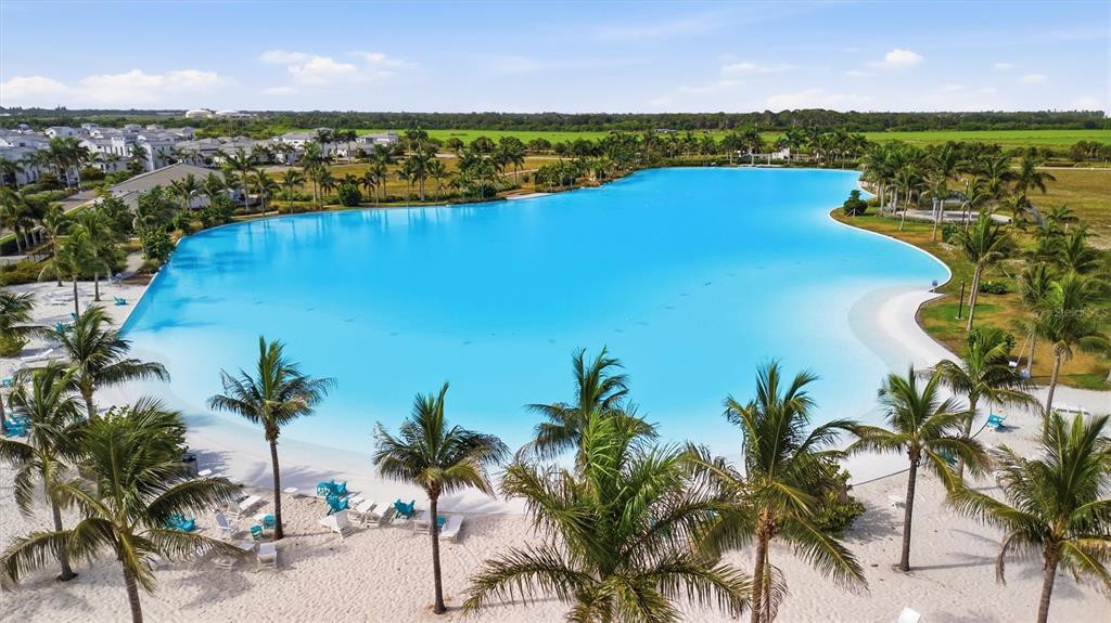 An aerial view of a large, bright blue swimming lagoon surrounded by palm trees — 6027 SALT GRASS STREET, BRADENTON, FL