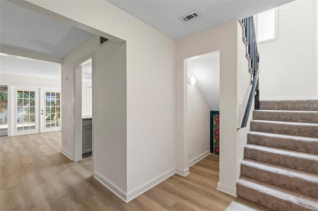 An interior view shows a staircase with carpeted steps, light wood flooring, and two doorways — 108 NORTHBROOK LANE, ORMOND BEACH, FL