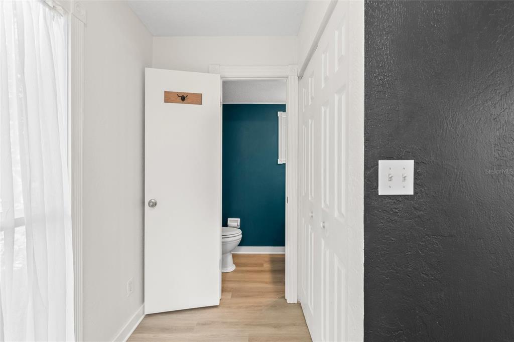 A hallway with a white door leading to a bathroom with a teal accent wall — 108 NORTHBROOK LANE, ORMOND BEACH, FL
