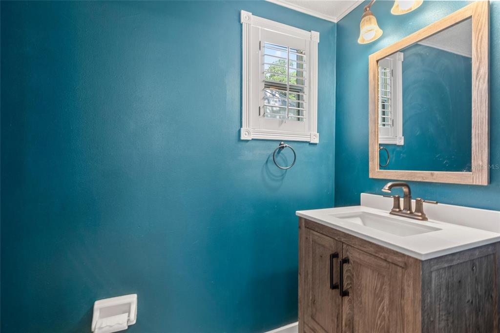 A bathroom features a wood vanity with a white countertop, teal walls, and a mirror — 108 NORTHBROOK LANE, ORMOND BEACH, FL