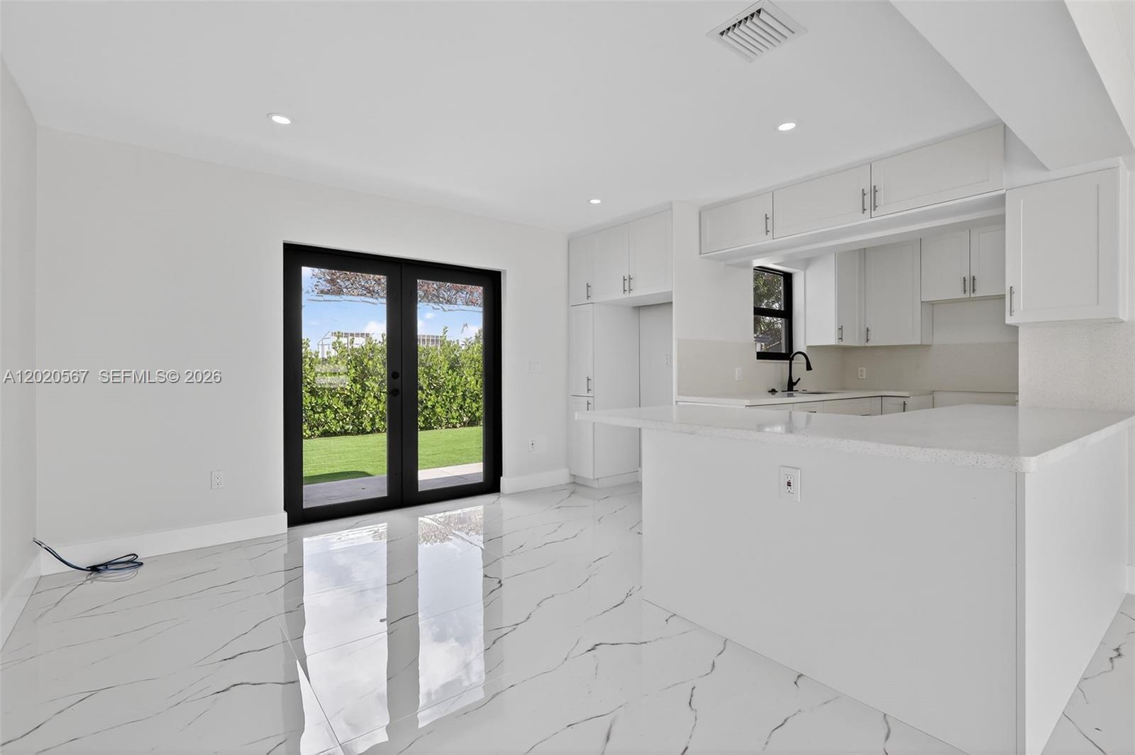 A white kitchen with marble-look tile floors features a breakfast bar and black-framed glass doors — 53 NW 68th St # 0, Miami FL 33150, MIAMI, FL