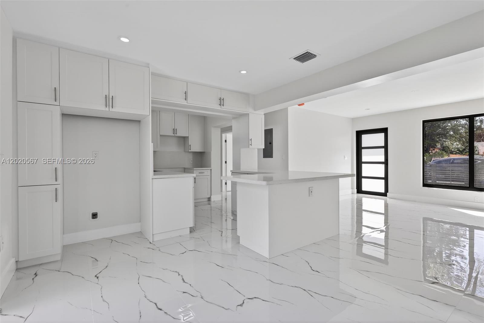 A modern kitchen features white cabinetry, a central island, and white marble-patterned tile flooring — 53 NW 68th St # 0, Miami FL 33150, MIAMI, FL