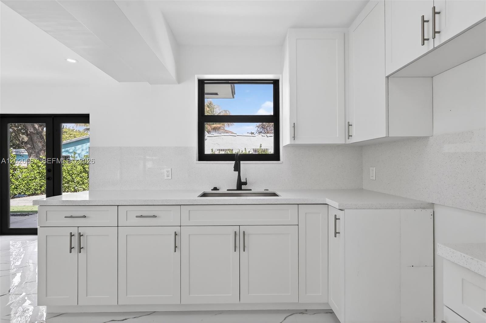 A modern kitchen features white cabinets, quartz countertops, a black faucet, and a window — 53 NW 68th St # 0, Miami FL 33150, MIAMI, FL
