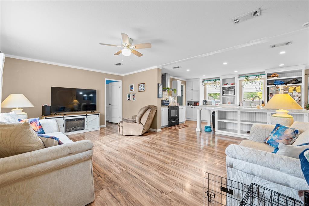 An open-concept living room and kitchen featuring light wood flooring and neutral wall colors — 12275 CROSS STREET, LARGO, FL