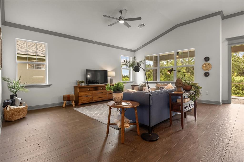 A living room features wood-look tile flooring, a vaulted ceiling, and a blue sofa — 7911 LAKE JAMES BOULEVARD, LAKELAND, FL