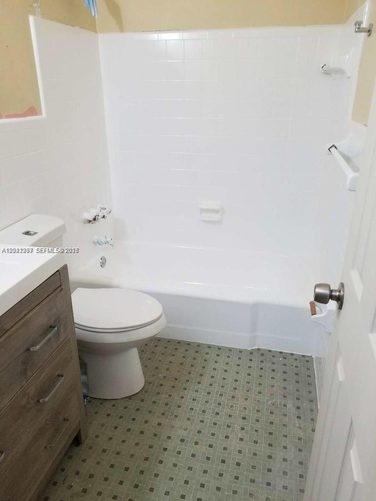 A bathroom features a white bathtub, a toilet, and a wooden vanity cabinet — HOLLYWOOD, FL