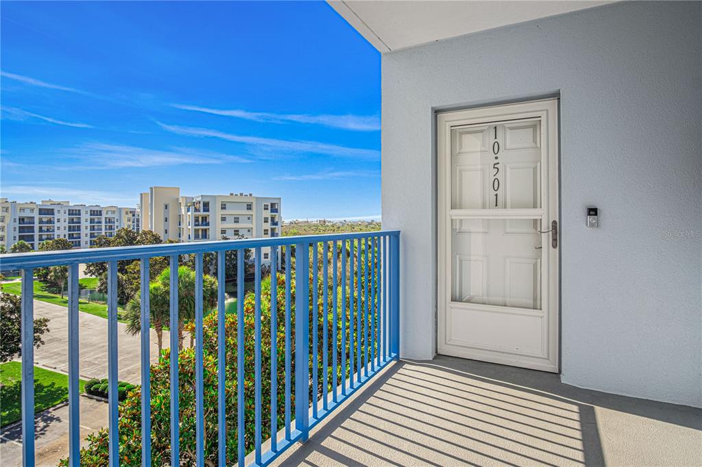 A balcony with a blue metal railing overlooks a parking lot and nearby apartment buildings — 5300 S ATLANTIC AVENUE UNIT 10501, NEW SMYRNA BEACH, FL