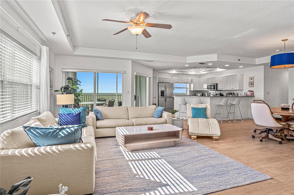 An open-concept living room and kitchen feature light wood flooring, a ceiling fan, and balcony views — 5300 S ATLANTIC AVENUE UNIT 10501, NEW SMYRNA BEACH, FL
