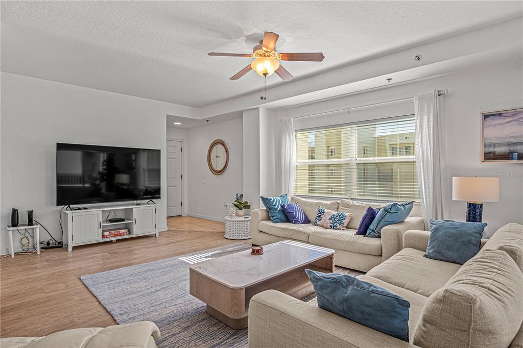 A living room features a white sofa, a marble coffee table, and a large television — 5300 S ATLANTIC AVENUE UNIT 10501, NEW SMYRNA BEACH, FL