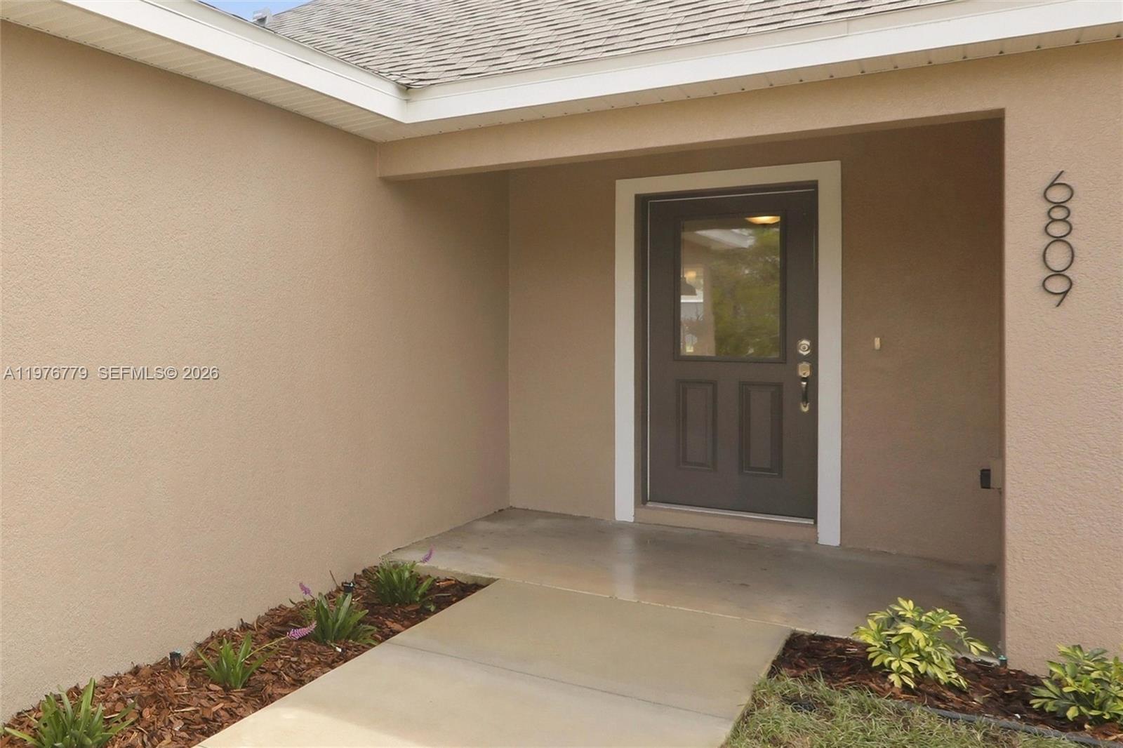 The exterior entrance features a concrete walkway leading to a dark brown front door — 6809 Dickinson Drive, Sebring FL 33872, SEBRING, FL