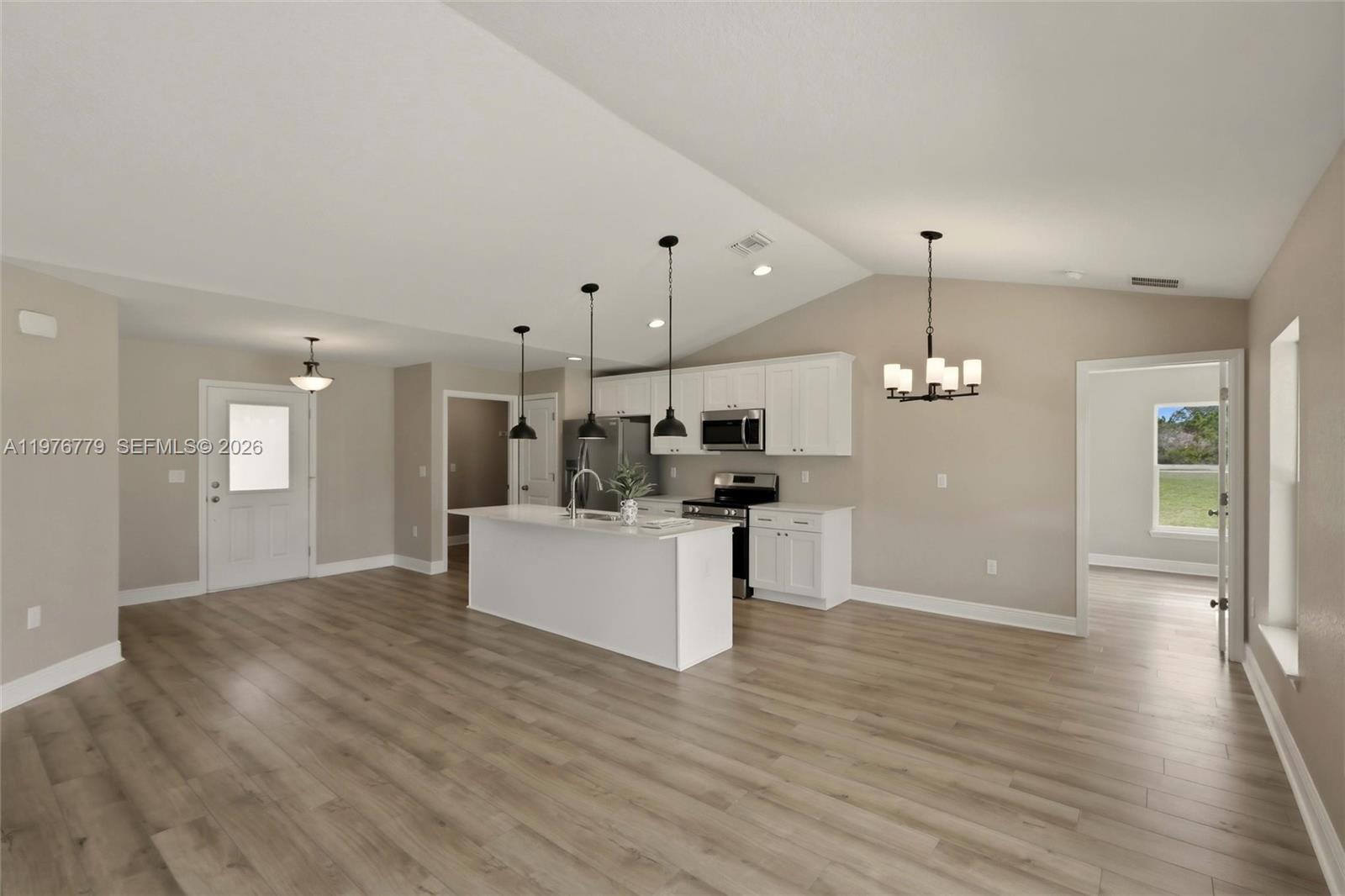 A kitchen with a white island, stainless steel appliances, and wood-look flooring — 6809 Dickinson Drive, Sebring FL 33872, SEBRING, FL