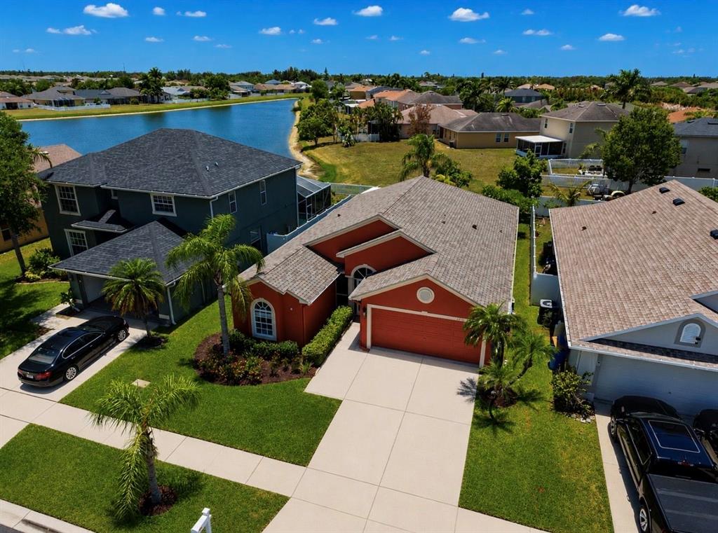 An aerial view shows a red-stucco house with a gray roof and a concrete driveway — 1836 RAVEN GLEN DRIVE, RUSKIN, FL