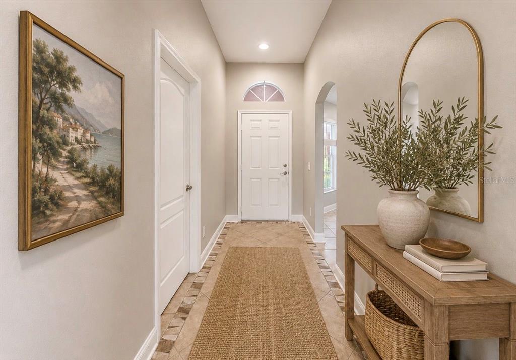A bright entryway features a tiled floor, a runner rug, a console table, and a mirror — 1836 RAVEN GLEN DRIVE, RUSKIN, FL
