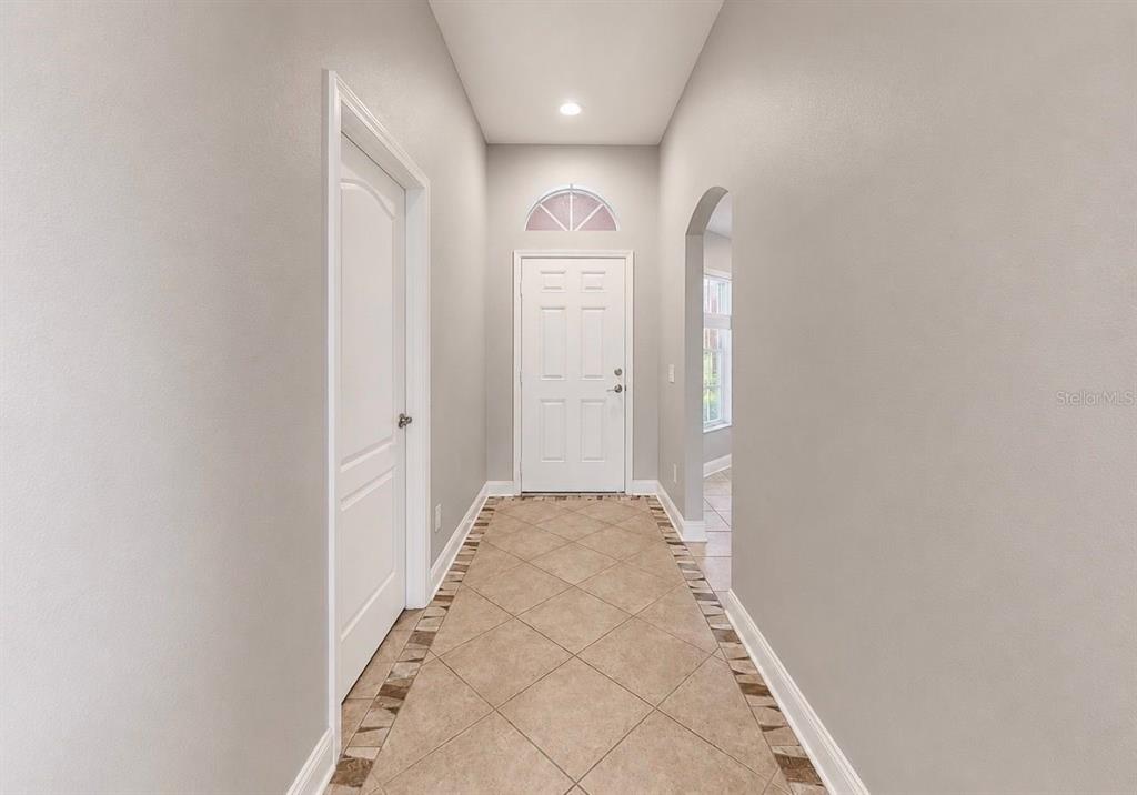 A tiled entryway features a white front door with a transom window and arched doorway — 1836 RAVEN GLEN DRIVE, RUSKIN, FL