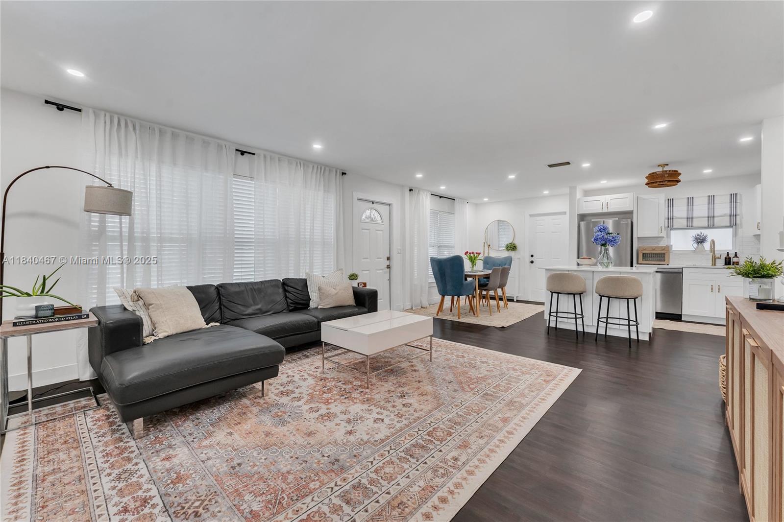 An open-concept living room and kitchen feature dark wood floors, a sectional sofa, and island seating — 2851 Washington St, Hollywood FL 33020, HOLLYWOOD, FL