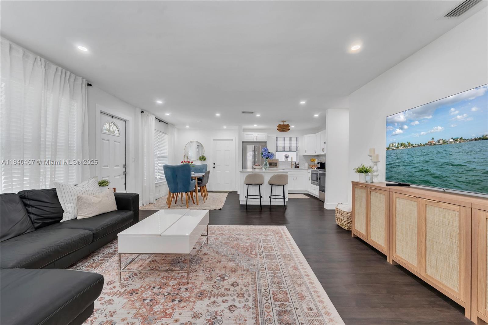 A living room and kitchen open-concept space features dark wood floors and a large television — 2851 Washington St, Hollywood FL 33020, HOLLYWOOD, FL