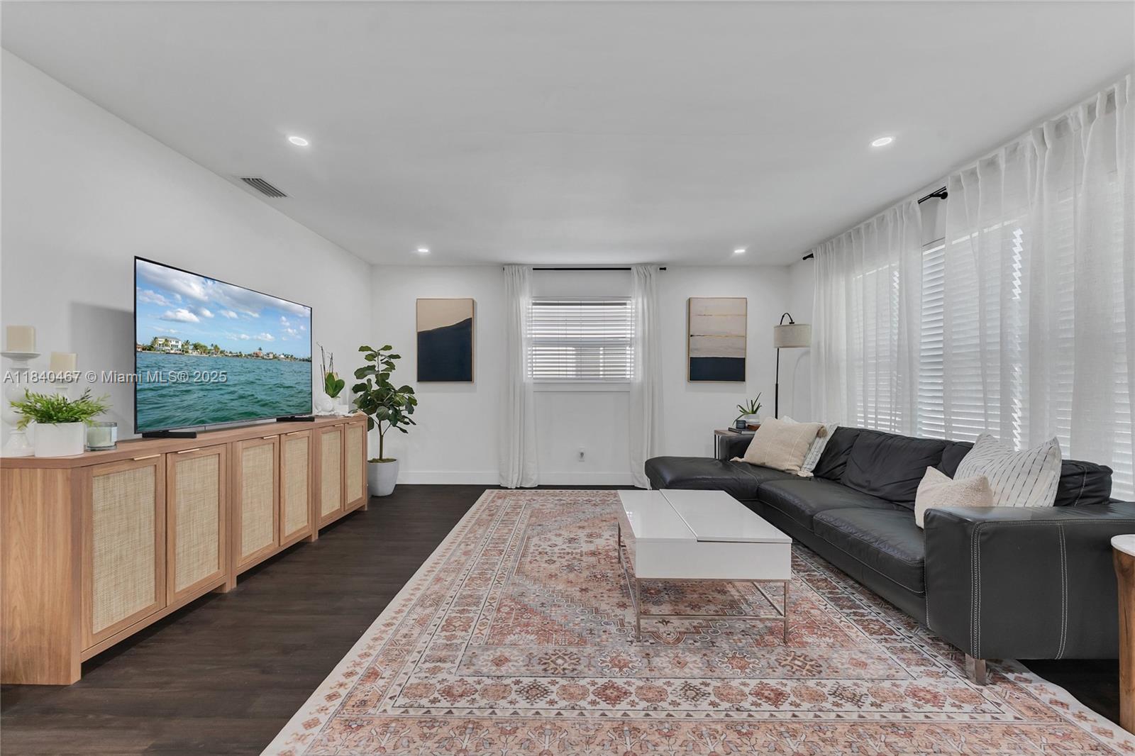 A living room features a black sectional sofa, a patterned rug, and a wooden media console — 2851 Washington St, Hollywood FL 33020, HOLLYWOOD, FL