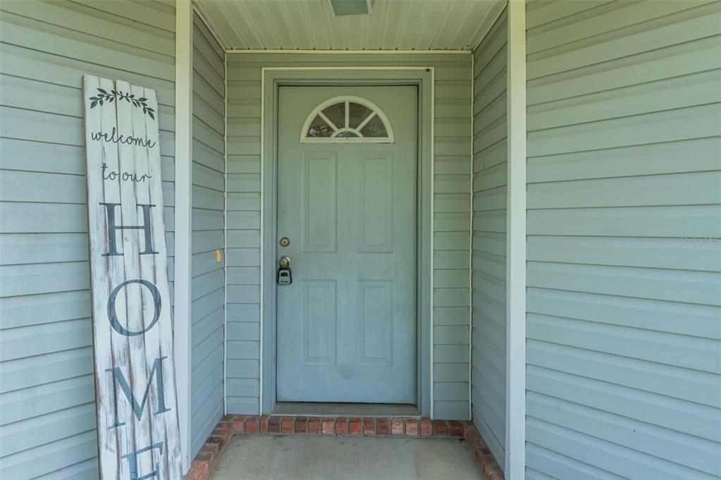 A light blue front door with a small arched window sits under a covered porch — 1206 EGO DRIVE, CRESTVIEW, FL
