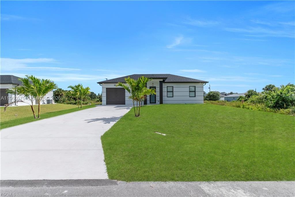 A single-story house with a white exterior, dark roof, and a concrete driveway — 711 Roma Ave, Lehigh Acres FL 33974, LEHIGH ACRES, FL