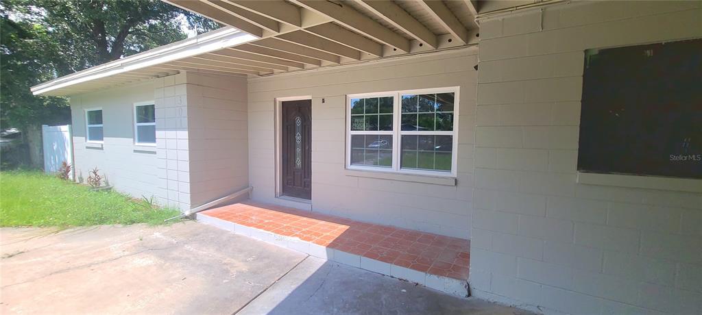 A house exterior features a concrete block facade, a tiled front porch, and a carport — 301 HOPE CIRCLE, ORLANDO, FL