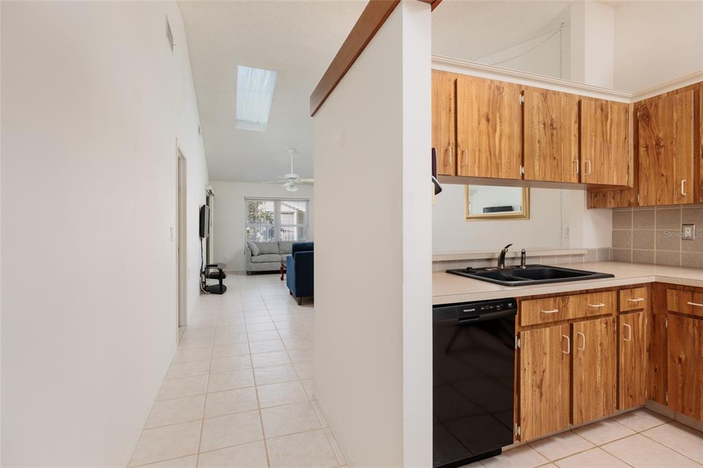 A kitchen with wood cabinets and a black sink overlooks a tiled living area — 216 SUN VISTA CT S, TREASURE ISLAND, FL