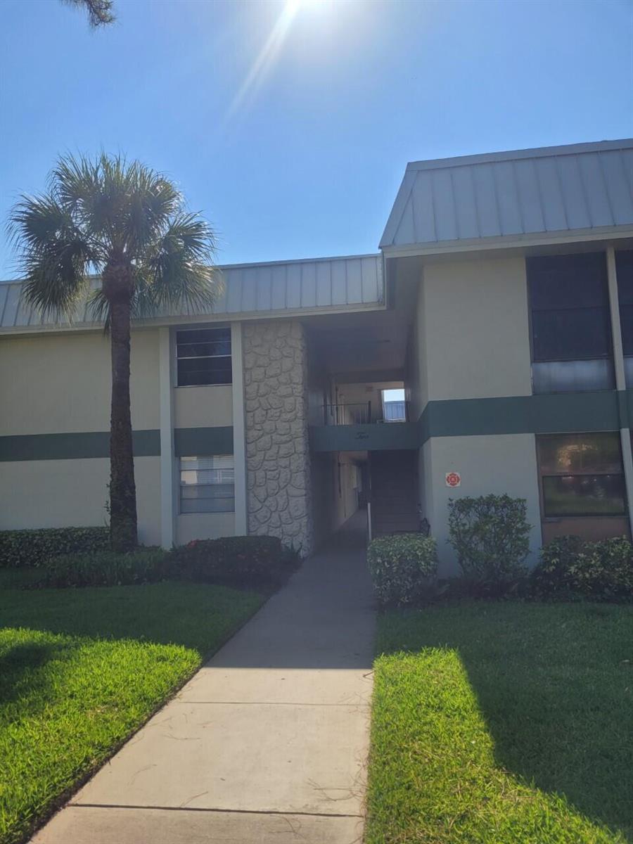 A two-story apartment building exterior features a stone-accented entryway, a palm tree, and walkways — 2302 Sunrise Boulevard # 201, Fort Pierce FL 34982, FORT PIERCE, FL