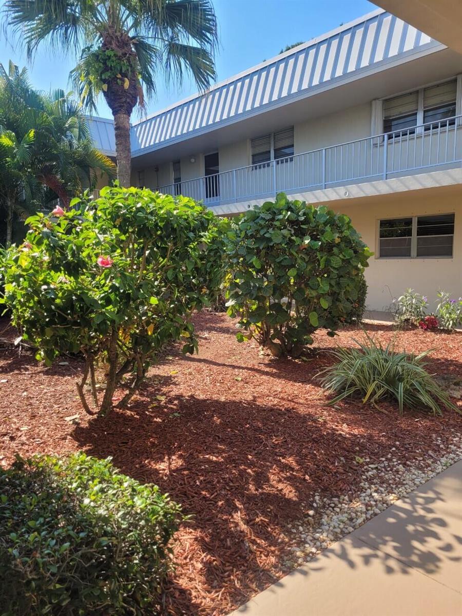 A two-story apartment building exterior features a landscaped courtyard with shrubs and a palm tree — 2302 Sunrise Boulevard # 201, Fort Pierce FL 34982, FORT PIERCE, FL