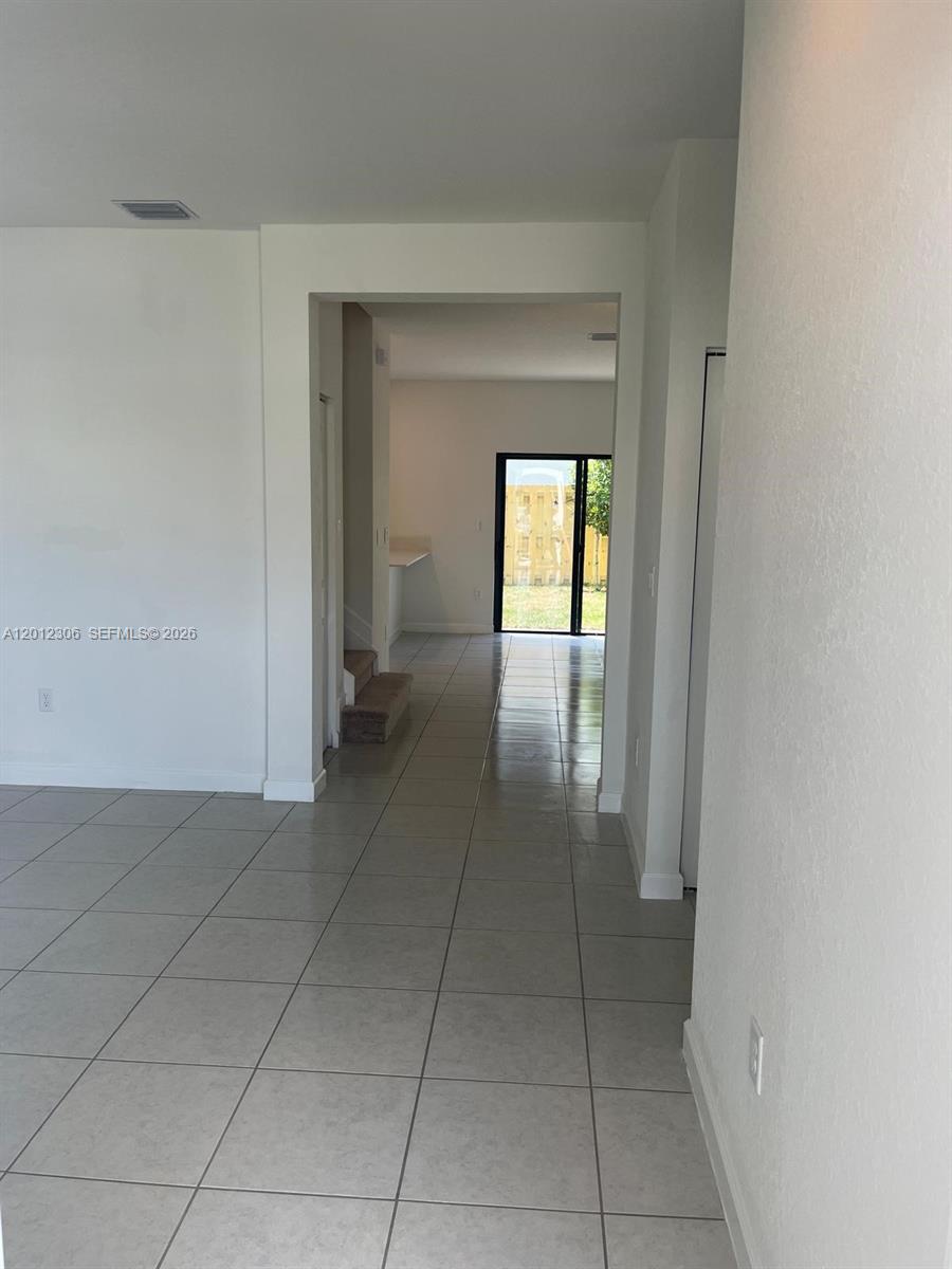 A tiled living area leads through an open doorway to a kitchen and sliding glass doors — 12912 SW 233rd Ter, Homestead FL 33032, HOMESTEAD, FL