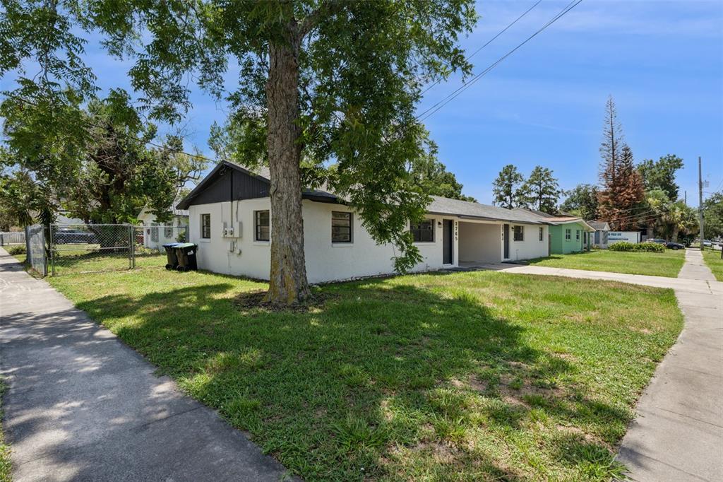 A single-story white stucco duplex with a flat roof and a large tree in front — 2763 & 2765 COOLIDGE AVENUE, ORLANDO, FL