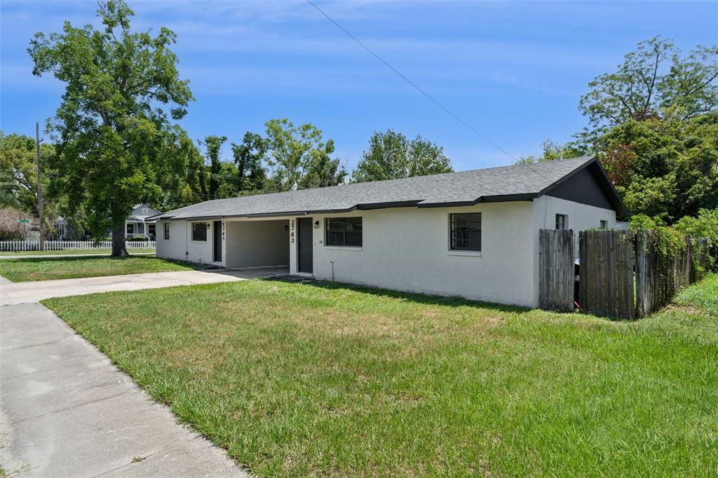 A single-story duplex with a shared carport and a wooden fence on a grassy lot — 2763 & 2765 COOLIDGE AVENUE, ORLANDO, FL