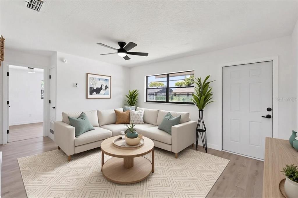 A living room features a beige sectional sofa, a round wooden coffee table, and light flooring — 2763 & 2765 COOLIDGE AVENUE, ORLANDO, FL