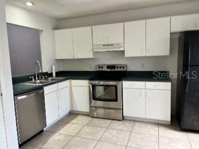 A kitchen with white cabinets, dark countertops, stainless steel appliances, and light-colored tile flooring — 2169 CYPRESS BAY BOULEVARD, KISSIMMEE, FL