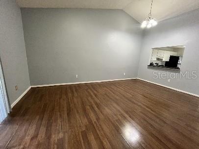 An empty living room with vaulted ceilings, light blue walls, and wood-look laminate flooring — 2169 CYPRESS BAY BOULEVARD, KISSIMMEE, FL