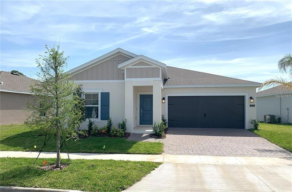 A single-story house with a beige stucco exterior, blue front door, and a paved driveway — 1373 BRENTWOOD DR, KISSIMMEE, FL