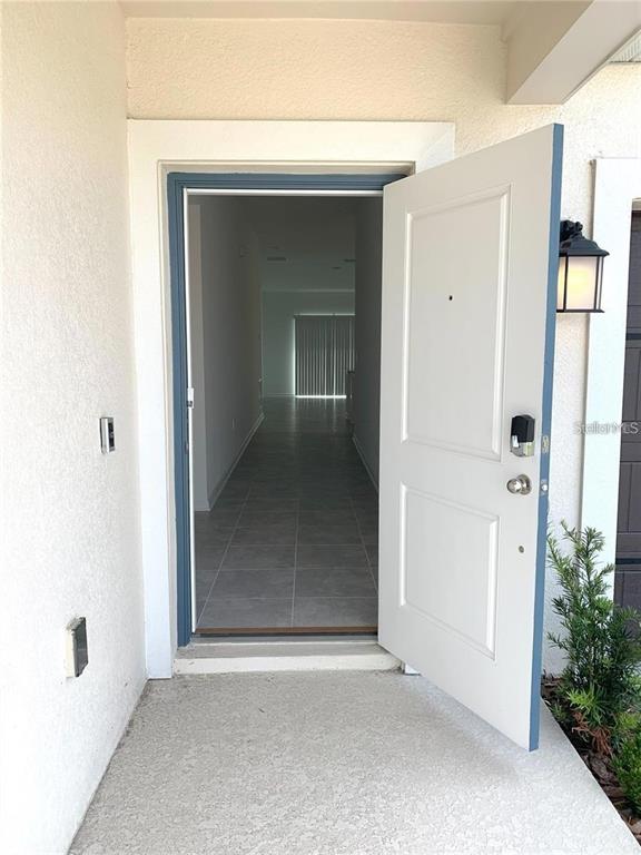 An open front door reveals a tiled entryway leading to a bright, empty interior hallway — 1373 BRENTWOOD DR, KISSIMMEE, FL