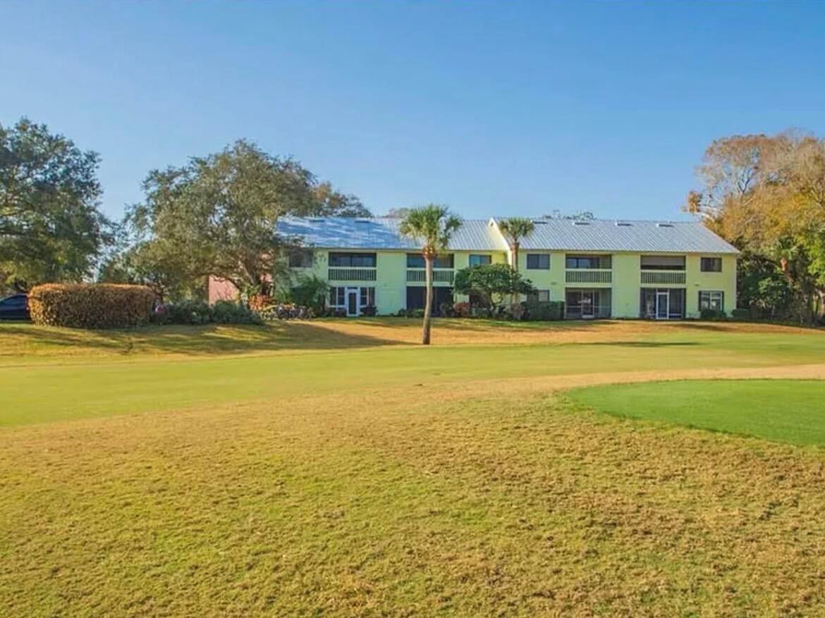 A two-story apartment building sits behind a grassy golf course fairway under a clear sky — 5790 Marina Drive # 2, Sebastian FL 32958, SEBASTIAN, FL