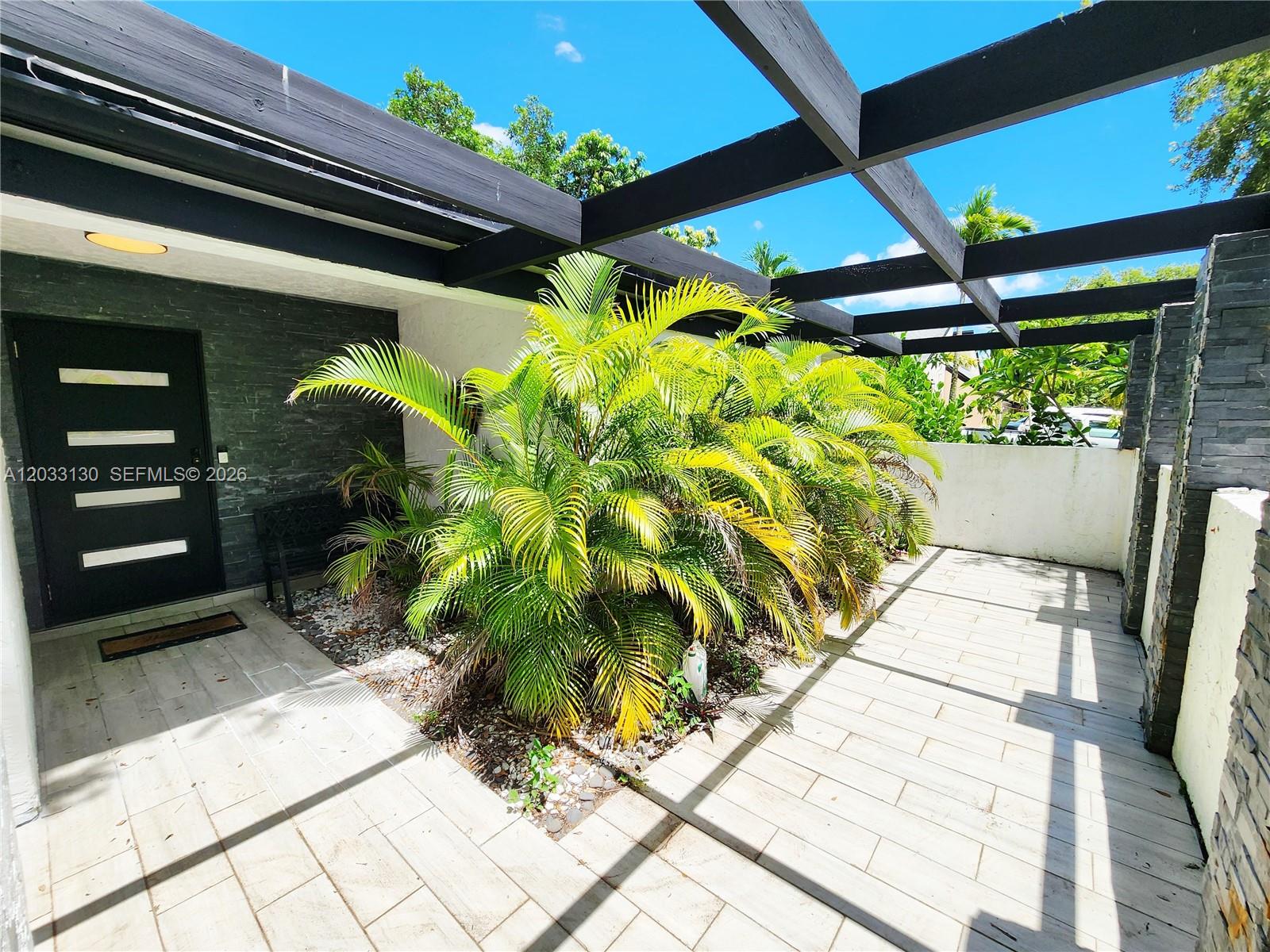 An outdoor patio features a pergola, stone accent walls, and a large palm plant — 4962 SW 95th Ave, Cooper City FL 33328, COOPER CITY, FL
