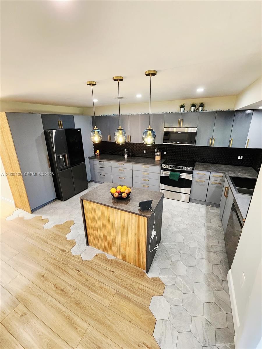 A modern kitchen features gray cabinets, a wood-paneled island, and a hexagonal tile floor — 4962 SW 95th Ave, Cooper City FL 33328, COOPER CITY, FL