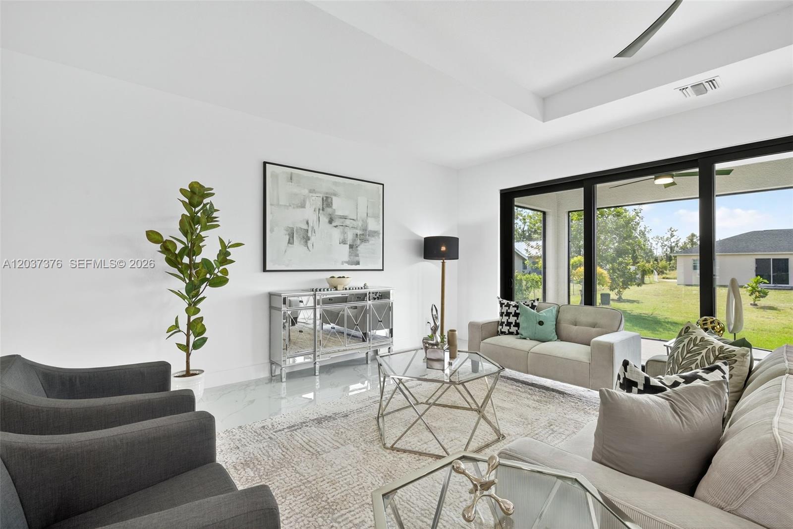 A modern living room features white walls, marble floors, a mirrored console, and glass doors — 4202 14th St SW, Lehigh Acres FL 33976, LEHIGH ACRES, FL