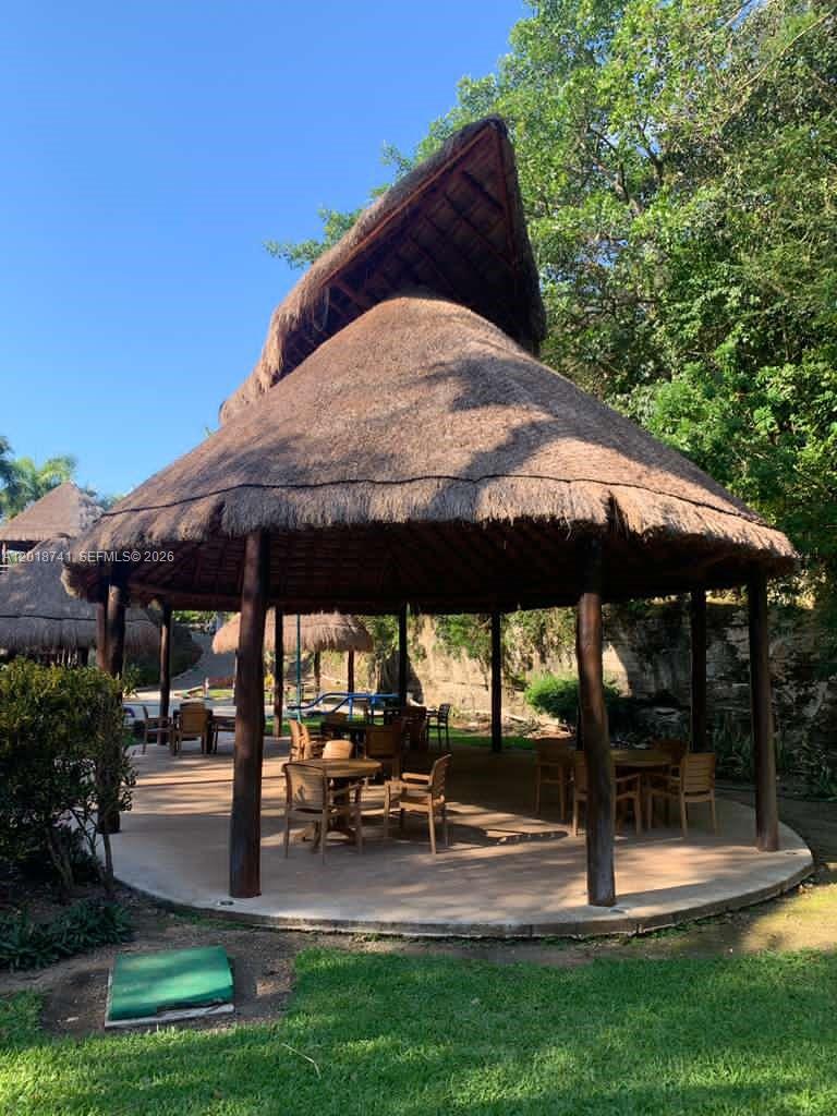 A thatched-roof gazebo with outdoor seating sits on a concrete patio in a garden — MZ10 L25 Calle Isla, TX 77586, TX