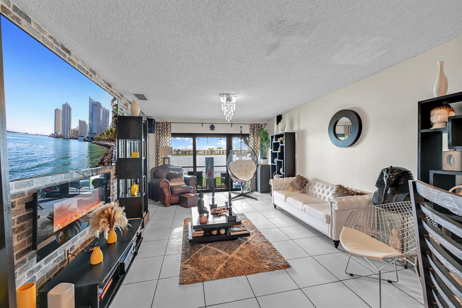 A living room features a large wall-mounted television, a white tufted sofa, and tile flooring — 627 Banks Road # 48, Margate FL 33063, MARGATE, FL
