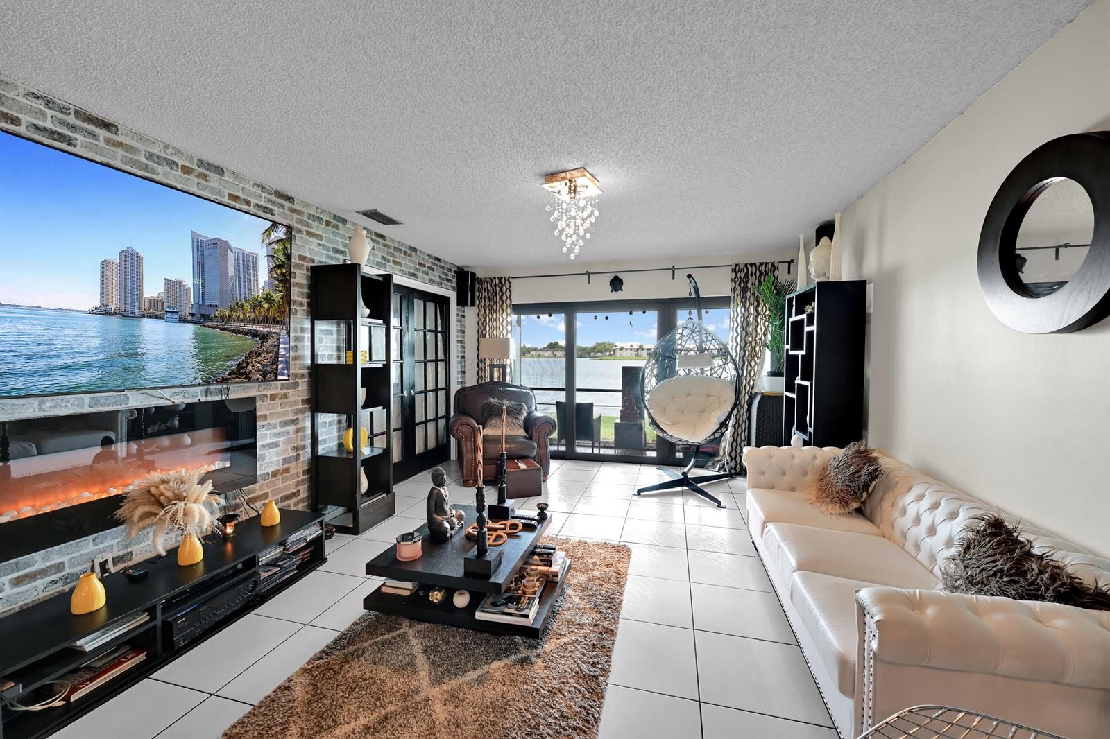 A living room features a brick accent wall with a fireplace, white sofa, and lake view — 627 Banks Road # 48, Margate FL 33063, MARGATE, FL