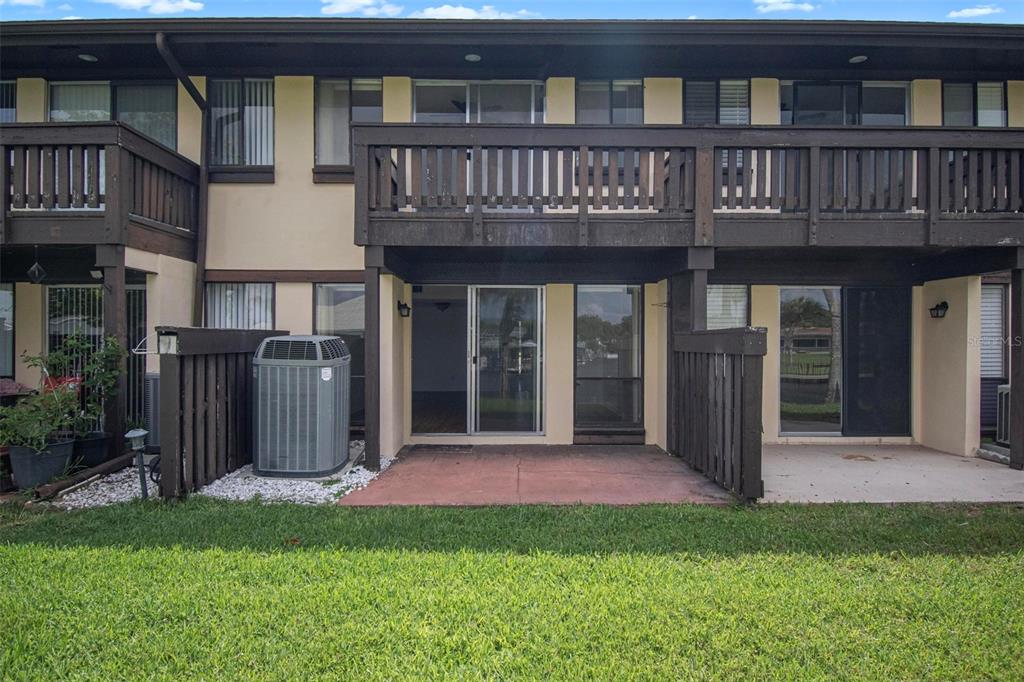 The exterior view shows a two-story townhouse with a ground-level patio and wooden balcony — 44 CLUB HOUSE DRIVE UNIT 106, PALM COAST, FL