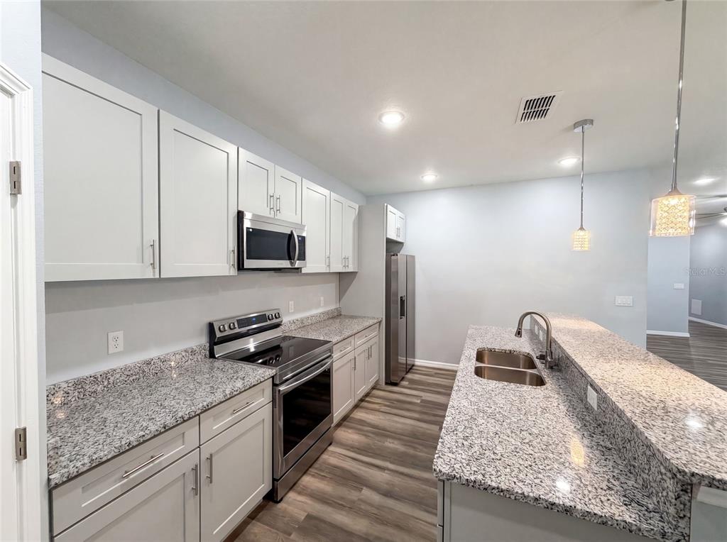 A kitchen features white cabinets, granite countertops, stainless steel appliances, and a breakfast bar — 1013 W 11TH STREET, SANFORD, FL