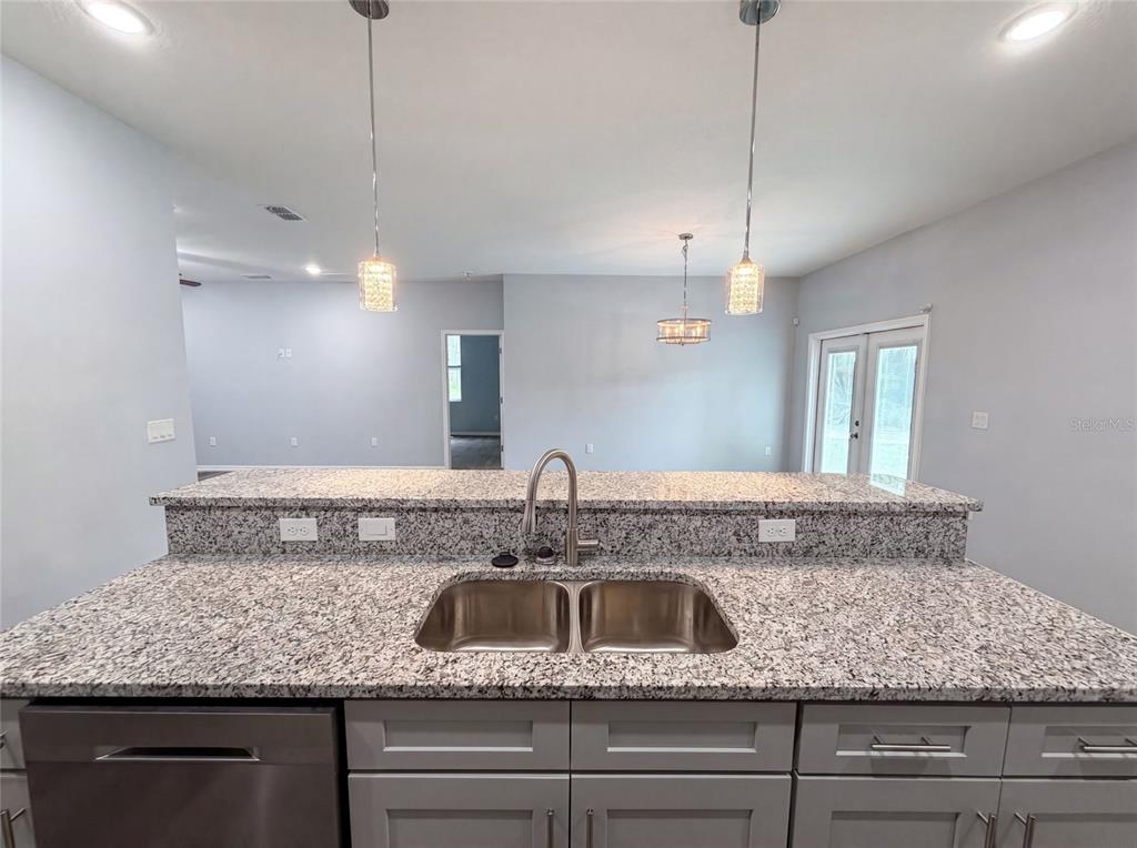 A kitchen island with a double-basin stainless steel sink and granite countertops faces a room — 1013 W 11TH STREET, SANFORD, FL