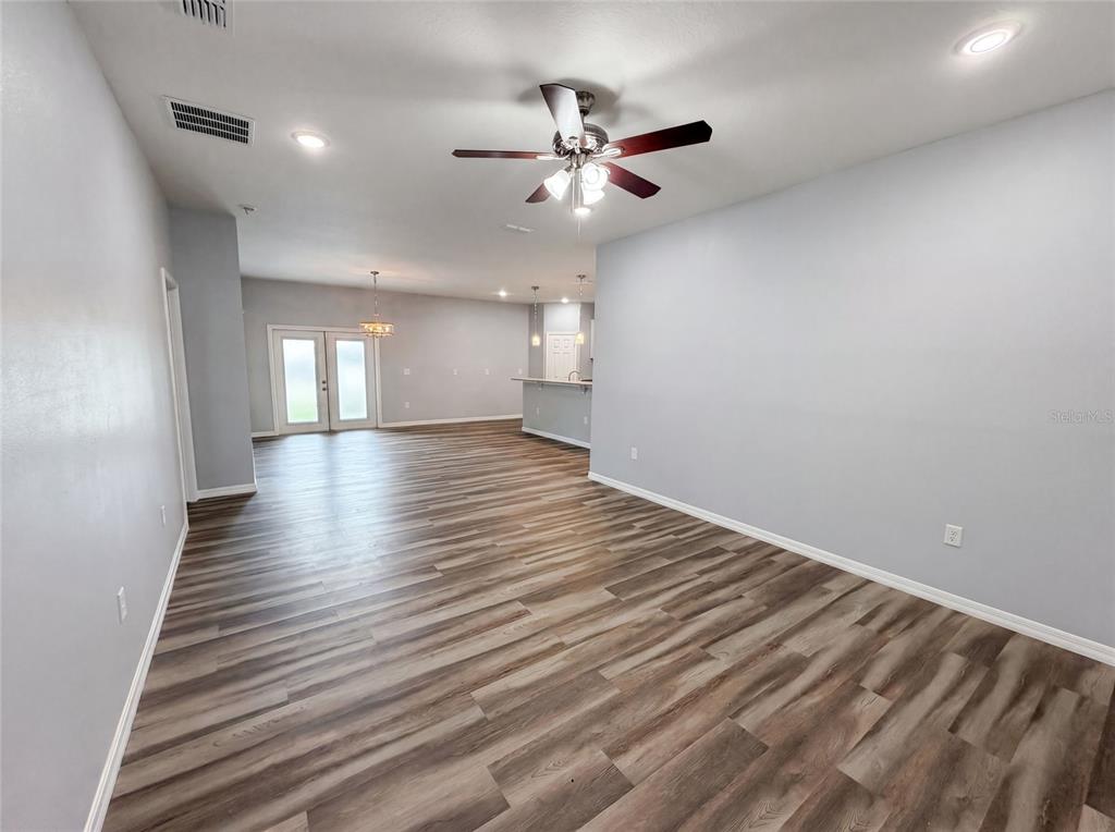 An open-concept living and dining area features light gray walls and wood-look plank flooring — 1013 W 11TH STREET, SANFORD, FL