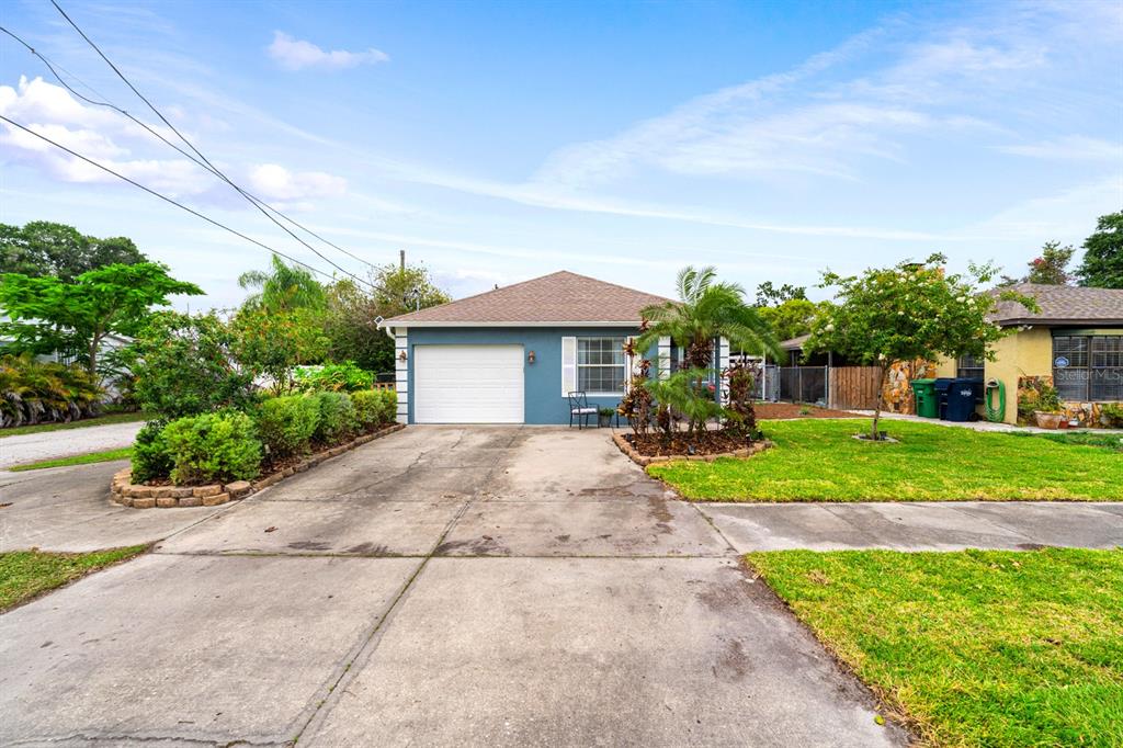 A blue single-story house with a white garage door and a concrete driveway — 3411 W NORTH B STREET, TAMPA, FL