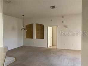 An interior view of a carpeted living room with arched wall cutouts and a chandelier — 3301 WHITESTONE CIRCLE UNIT 205, KISSIMMEE, FL