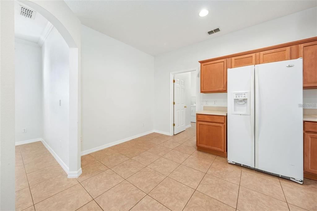 A kitchen area features light tile flooring, white walls, and wood cabinets with a refrigerator — 9651 OLD MARSH COURT, ORLANDO, FL