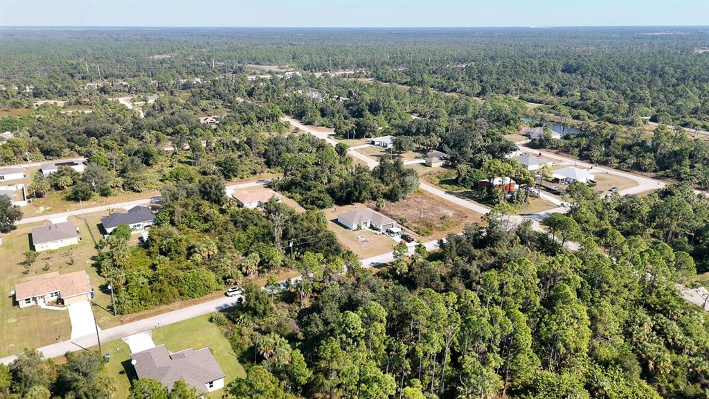 An aerial view shows several single-family homes surrounded by dense forest and paved roads — FILBERT STREET, NORTH PORT, FL